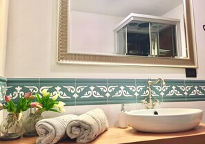 Une salle de bain avec un lavabo blanc, un miroir et des carreaux décoratifs.