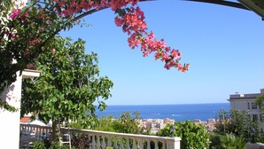 A balcony with a view of the sea and a cityscape.