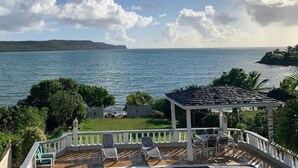 A seaside view with a gazebo, lounge chairs, and a clear sky.