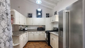 A kitchen with white cabinets, a stainless steel refrigerator, a microwave, and a gas stove.