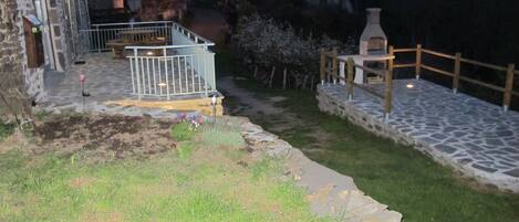 Un patio de piedra con una parrilla y un pequeño jardín.