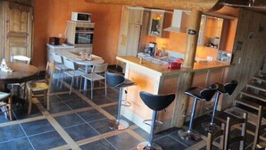 Ett mysigt kök med en central köksö, barstolar och en matplats med stolar.