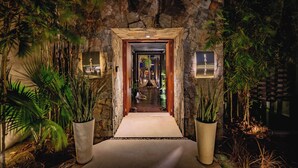Un arco de piedra que da paso a un pasillo flanqueado por macetas con plantas.