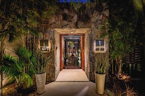 A stone archway leading to a hallway with potted plants on either side.