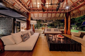 A modern interior with a thatched roof, a sofa, a coffee table, and a dining area.