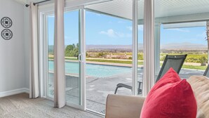 Ein Zimmer mit einer Schiebetür zu einem Poolbereich, einem Sessel und einem roten Kissen.
