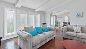 Ein geräumiges Wohnzimmer mit zwei Sofas, einem Couchtisch und einem Essbereich im Hintergrund.