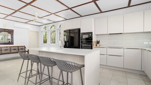 A modern kitchen with white cabinetry, a central island with bar stools, and a ceiling with wooden beams.