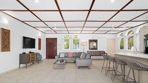 A spacious living area with a sofa, coffee table, and a bar area with stools.