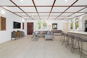 A spacious living area with a sofa, coffee table, and a bar area with stools.