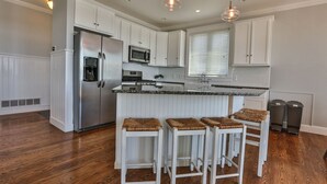 A modern kitchen with white cabinetry, stainless steel appliances, and a central island with bar stools. - AMAZING Lakefront And Well Designed Lakehouse: That Is Sure To Please (Romulus)