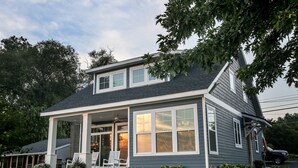 A two-story house with a covered porch, large windows, and a well-maintained lawn. - AMAZING Lakefront And Well Designed Lakehouse: That Is Sure To Please (Romulus)