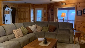 Un salon chaleureux avec un canapé d’angle, une table basse en bois et un ventilateur de plafond.