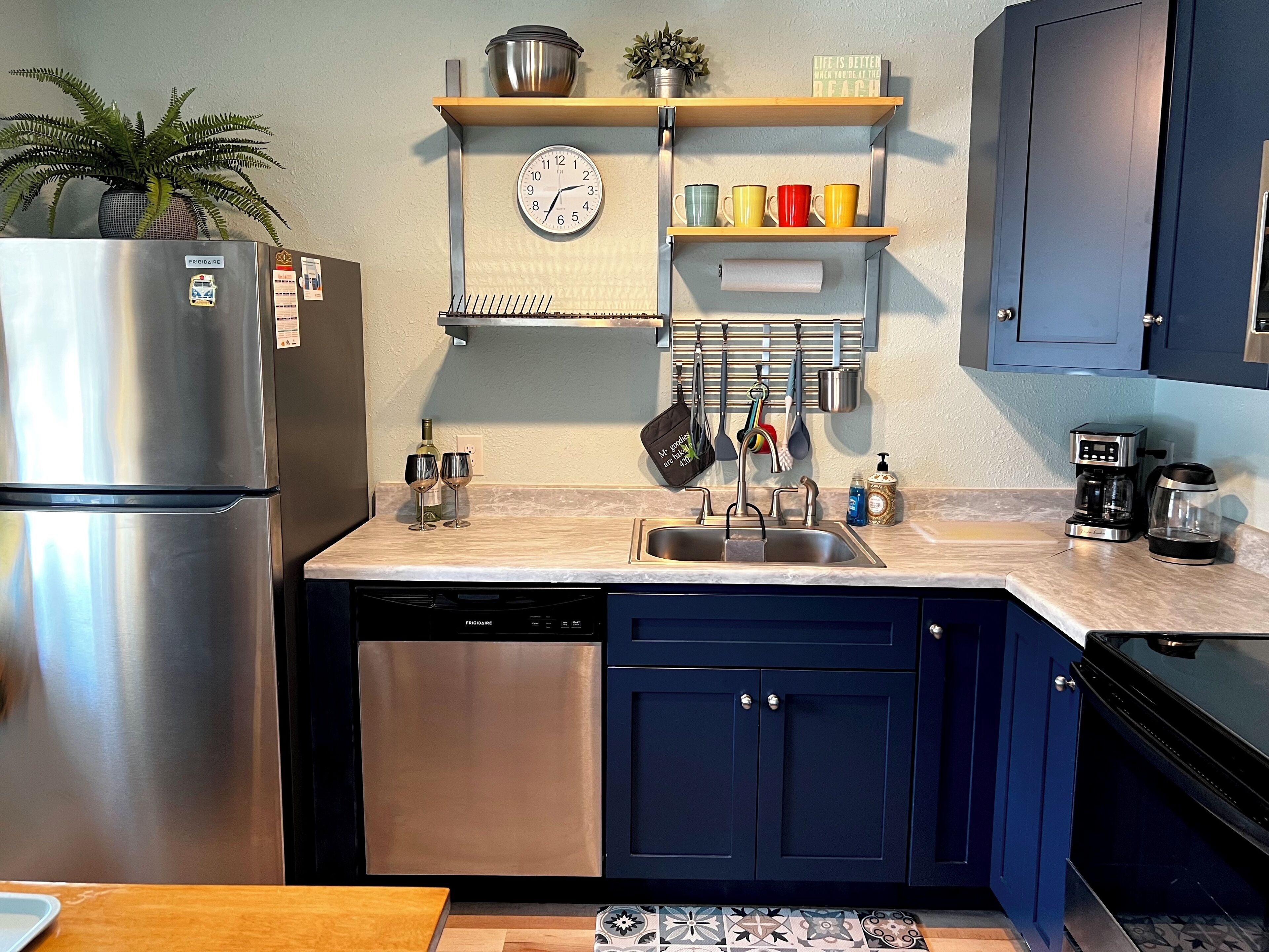 Una cocina con un refrigerador de acero inoxidable, un lavaplatos y una cafetera.
