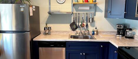 Una cocina con un refrigerador de acero inoxidable, un lavaplatos y una cafetera.