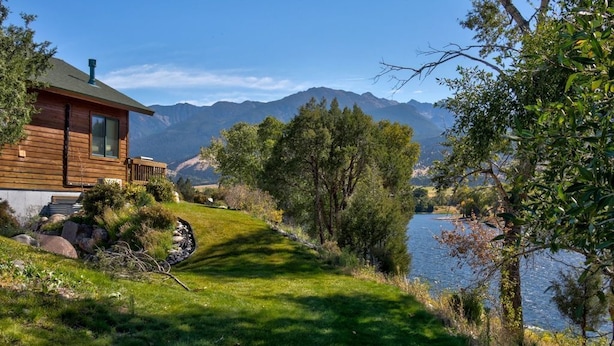 Una cabaña de madera con vistas a montañas y un lago.