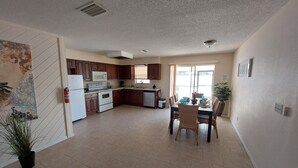 A spacious kitchen with modern appliances, a dining area with chairs, and a large window providing natural light.