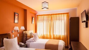 A hotel room with two beds, a desk, a TV, and a window with curtains. - Inti Punku Alameda Inn (Machu Picchu)