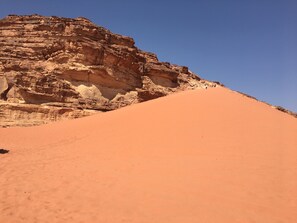 Wüstenlandschaft mit einer markanten Felsformation und einem sandigen Hügel.