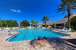 A swimming pool with lounge chairs and palm trees.