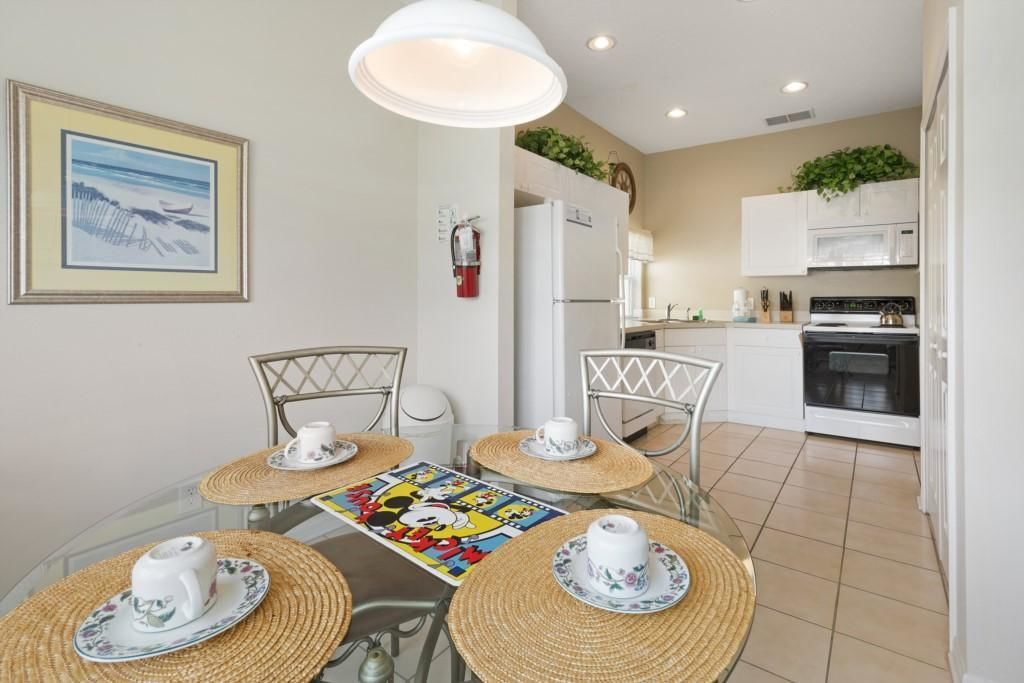 A dining area with a glass table, four chairs, and a tablecloth featuring a cartoon character.