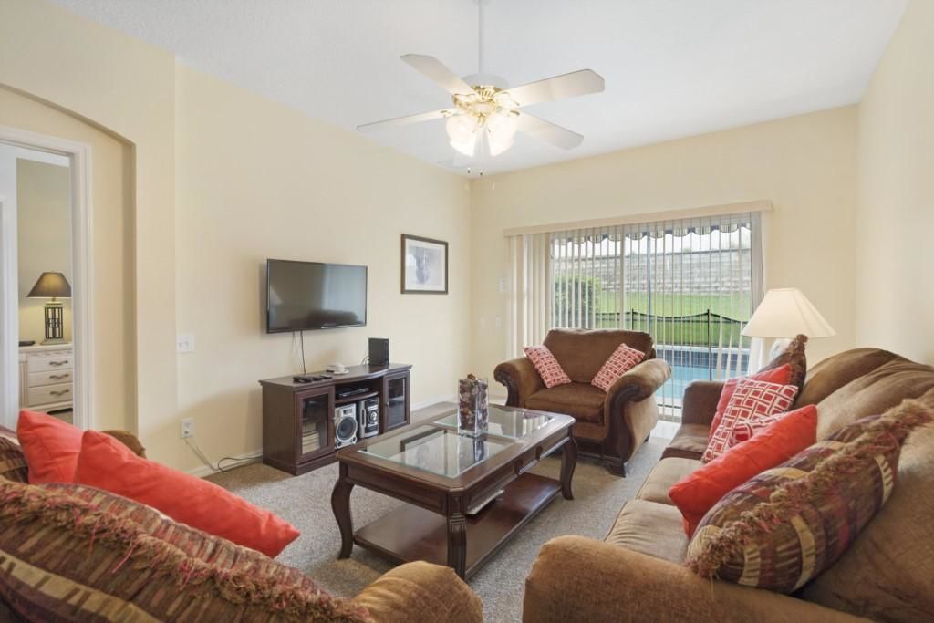 A living room with a ceiling fan, a flat-screen TV, a sofa set, and a coffee table.