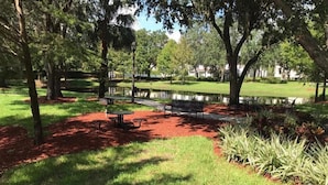 Un parque con un estanque, bancos y mesas de picnic.