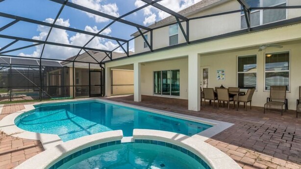 A swimming pool with a glass ceiling, outdoor seating, and a patio area.