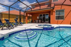 Uma piscina com área de estar embutida, rodeada por espreguiçadeiras e um alpendre coberto.