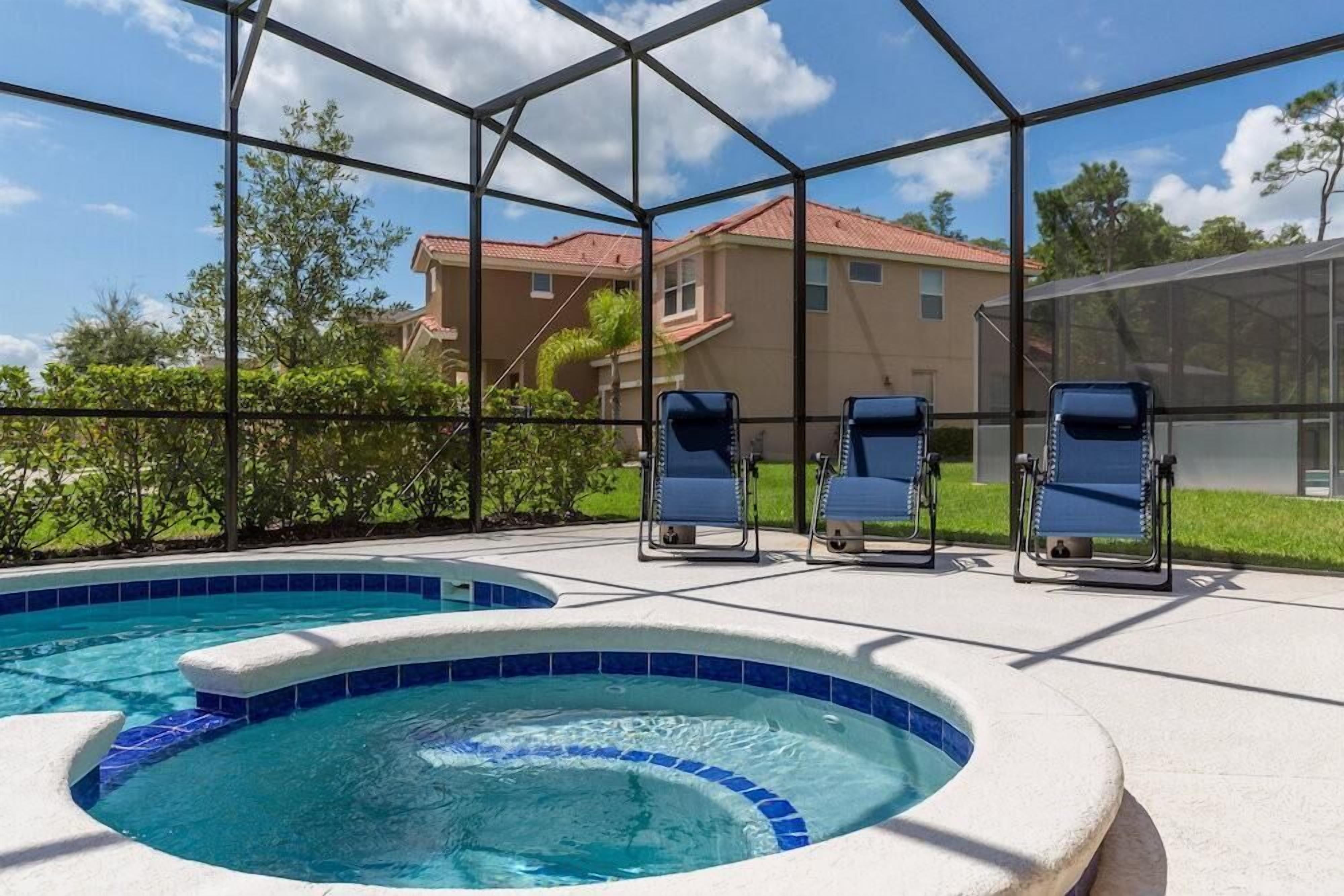 Piscina com hidromassagem, cercada por um compartimento de vidro, e três espreguiçadeiras.