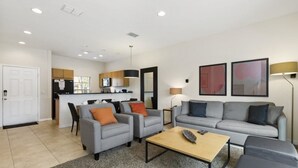 A modern living room with two grey sofas, a coffee table, and a kitchen area in the background. - Villa Magical - Encantada Resort (Kissimmee)