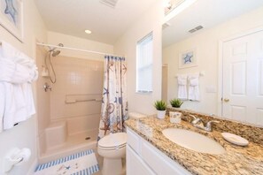 Une salle de bain avec une douche, des toilettes et deux lavabos.