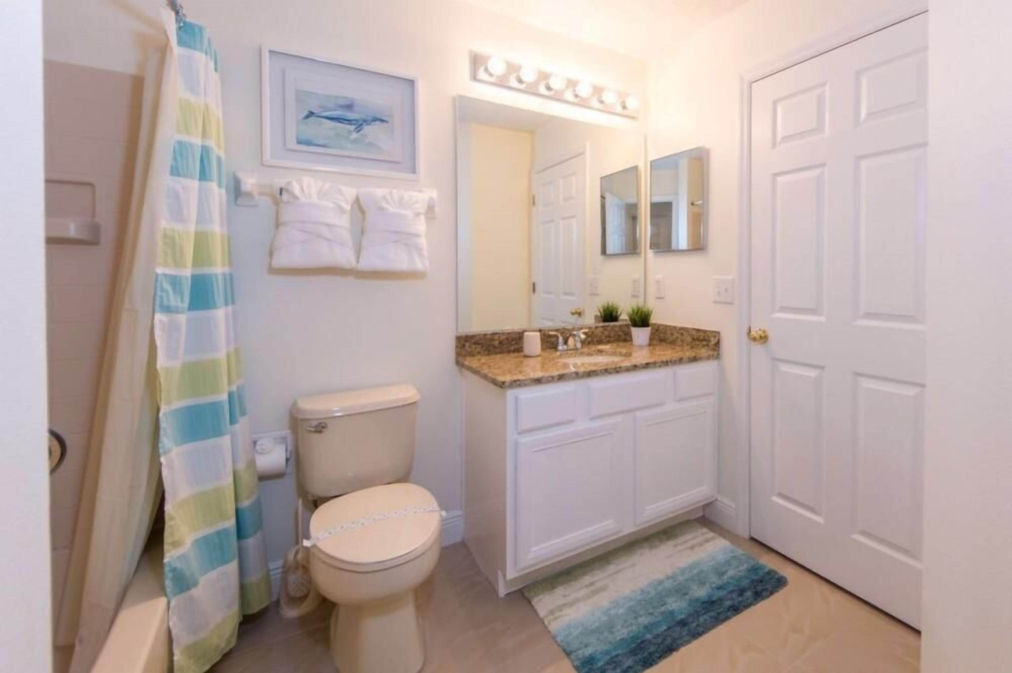 A bathroom with a toilet, sink, and shower curtain.