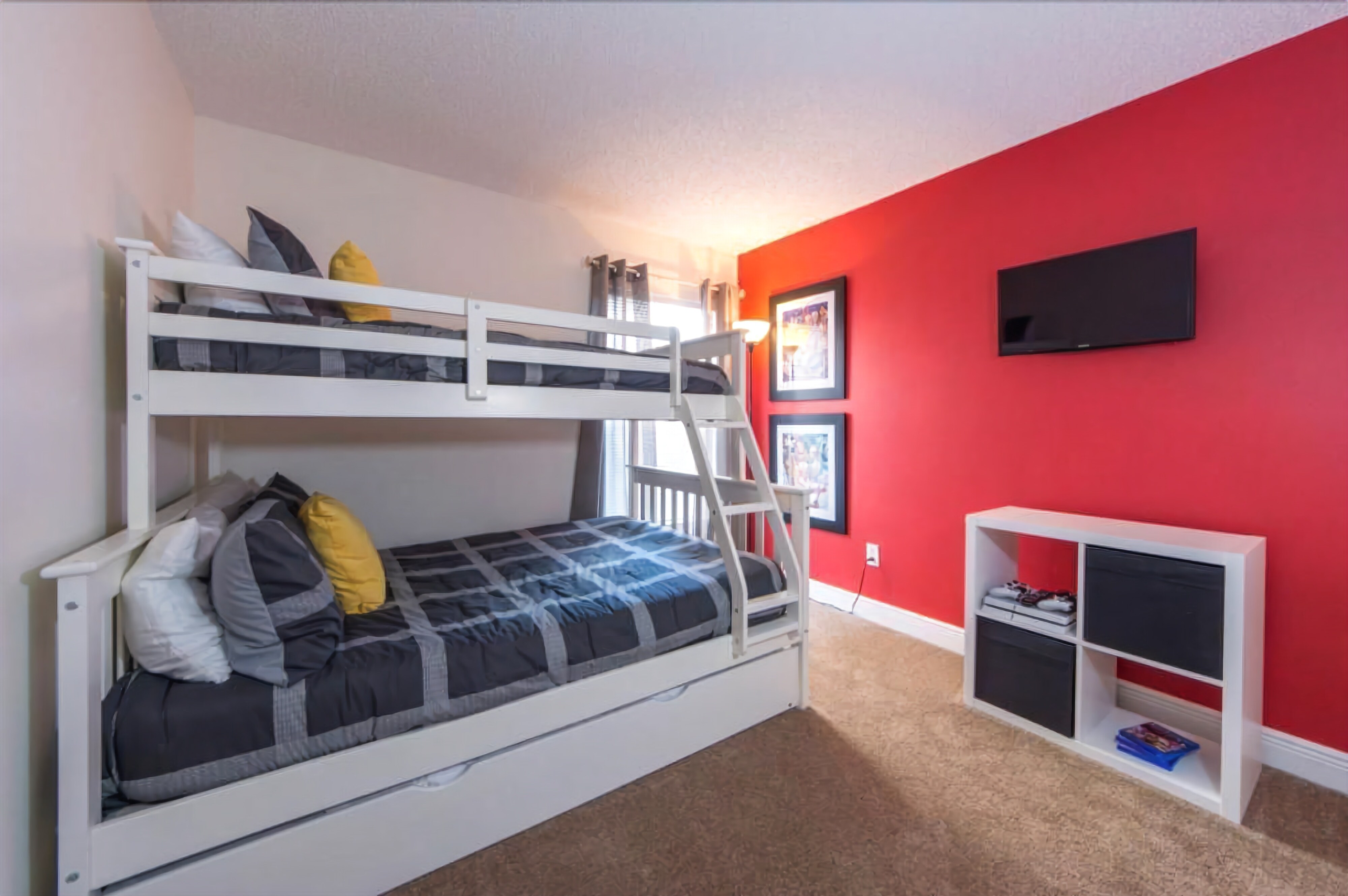 A bunk bed with a ladder, a TV mounted on the wall, and a small white shelf unit.