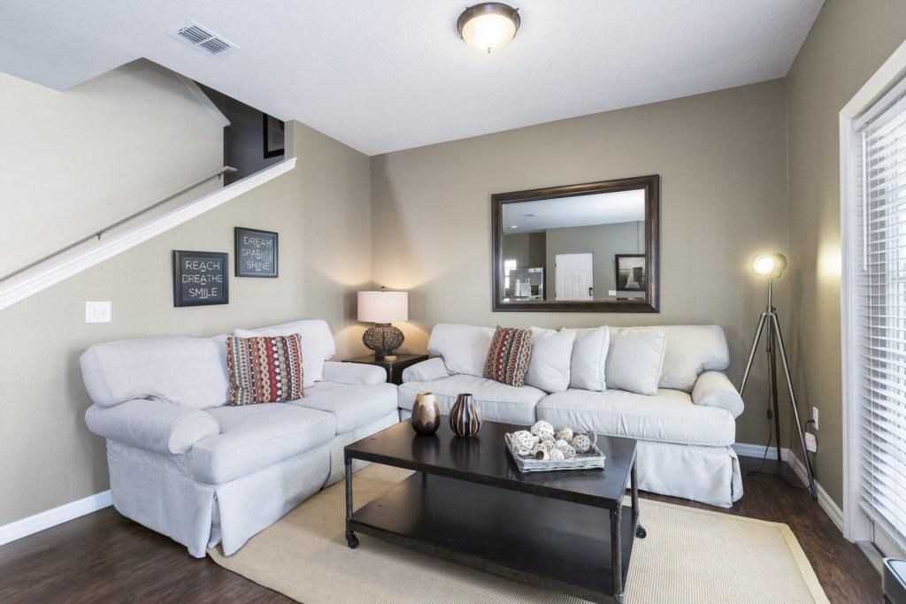 A living room with a white sectional sofa, a coffee table, a lamp, and a mirror on the wall.