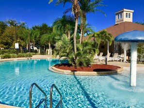 A swimming pool with a fountain, surrounded by palm trees and lounge chairs. - Villa Cristina - Lucaya Village (Kissimmee)