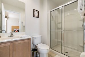 A modern bathroom with a glass shower enclosure, a white toilet, and a vanity with a mirror.