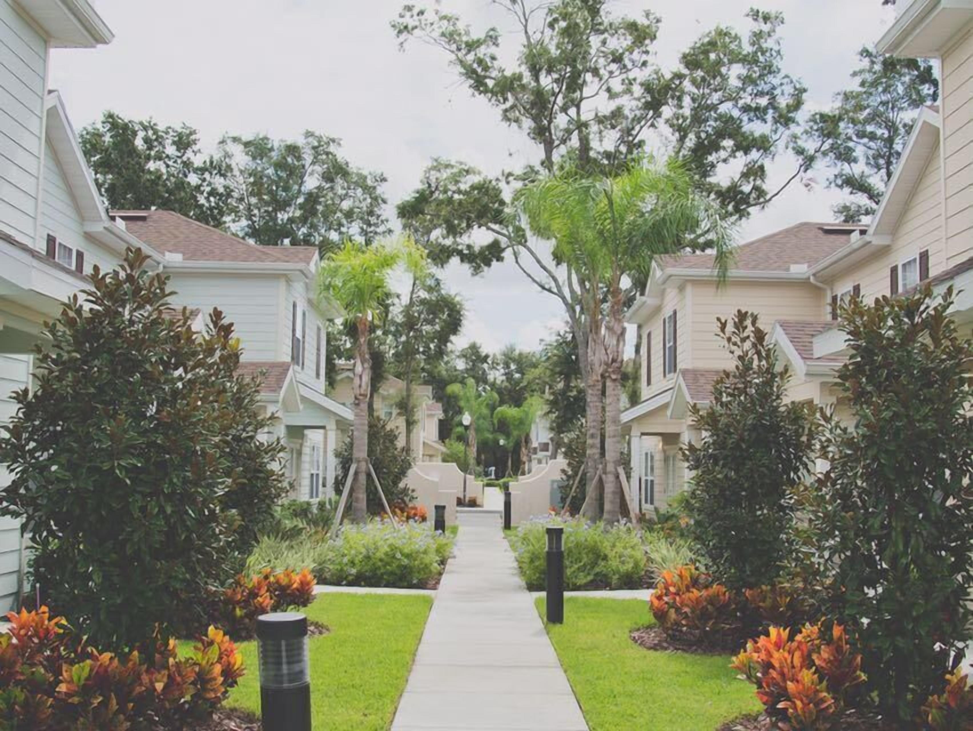 Una calle residencial con casas a ambos lados, un paseo central y jardines bien cuidados.
