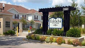 A gated entrance to Lucaya Village with a sign displaying the name and address. - Villa Fonseca - Lucaya Village (Kissimmee)