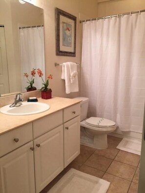 A bathroom with a sink, toilet, and shower curtain. - Villa Minnie - Lucaya Village (Kissimmee)