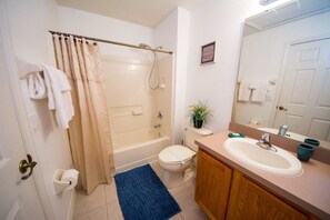 A bathroom with a bathtub, toilet, sink, and a mirror.