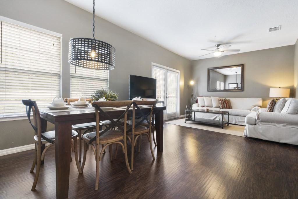 A modern living room with a dining area, a sofa, a TV, and a ceiling fan.