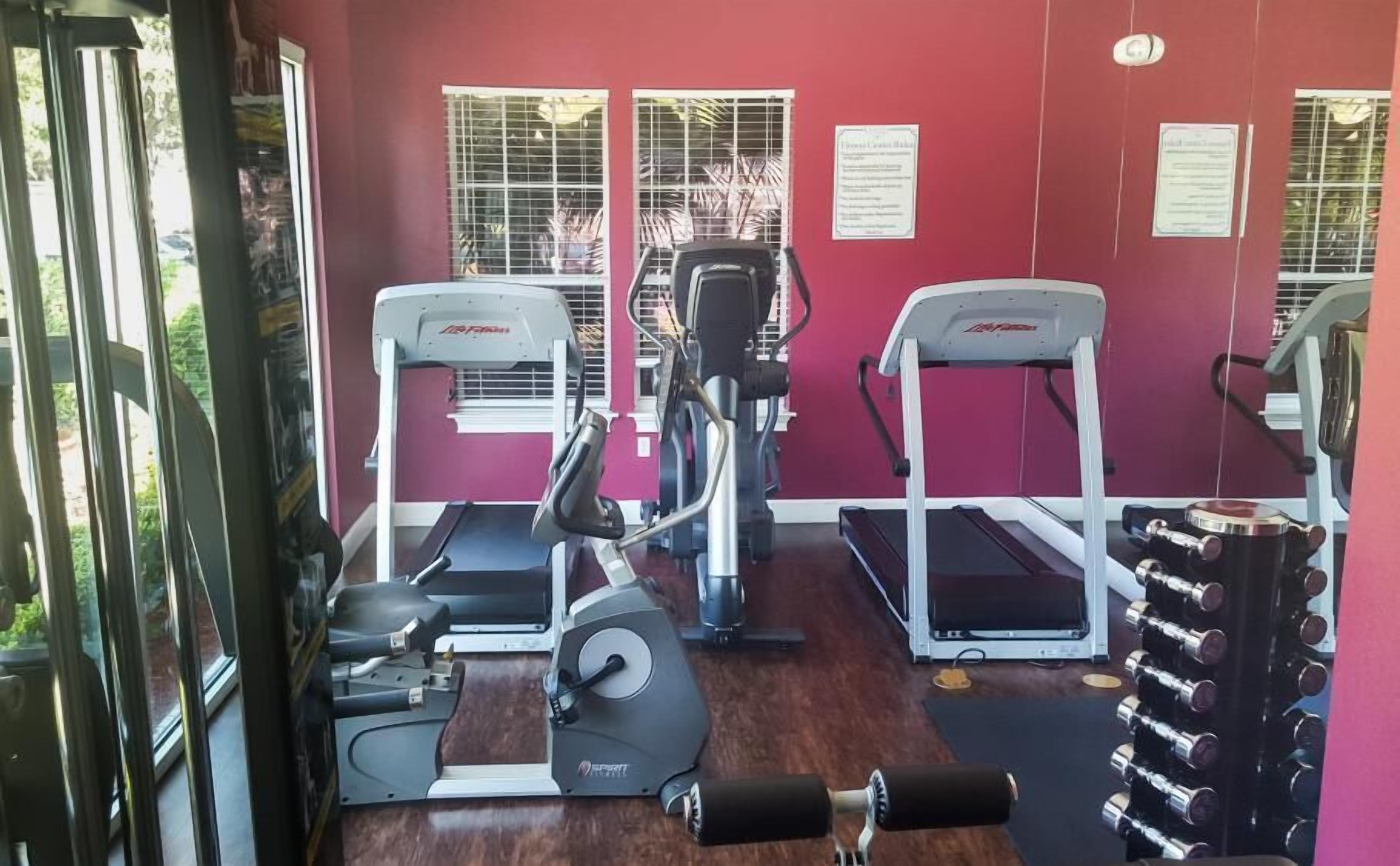 Une salle de sport équipée de tapis de course, de vélos elliptiques et de bancs de musculation.