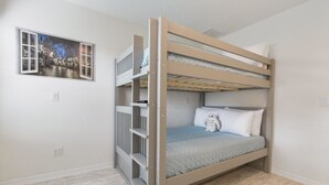 A bunk bed with a cityscape mural on the wall, a white door, and a light-colored floor. - Villa Rodrigues - Encantada Resort (Kissimmee)