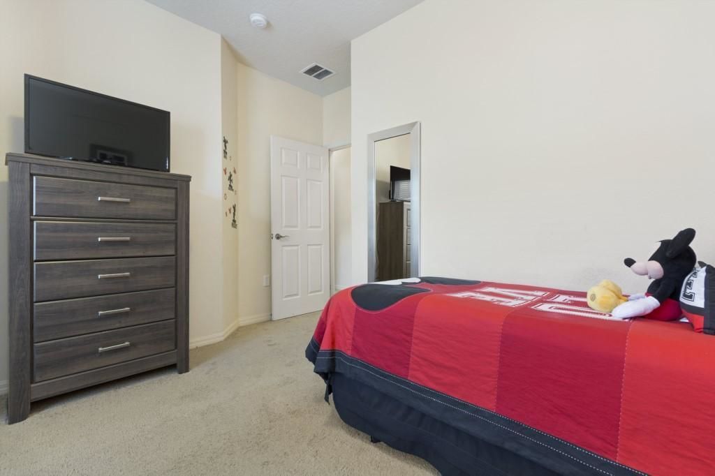 A bedroom with a bed, a dresser, and a television on top.