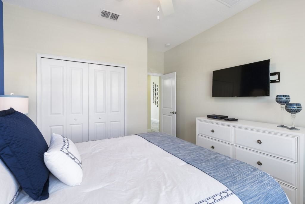 A bedroom with a bed, a dresser, a television, and a door.