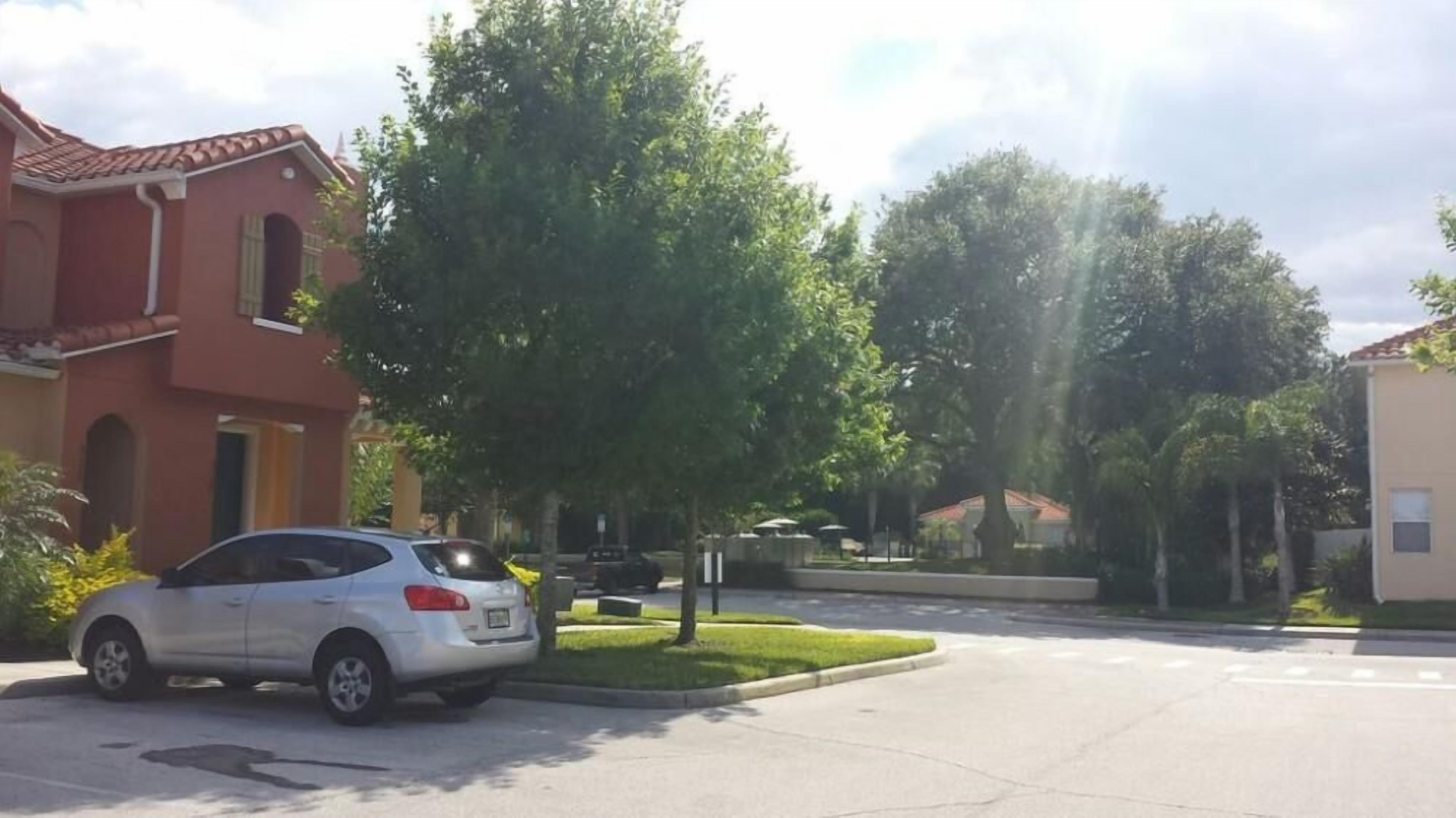 Una calle residencial con un coche aparcado, casas y árboles.