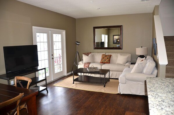 A living room with a flat-screen TV, a sofa, a coffee table, and a lamp.