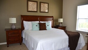 A neatly made bed with a white comforter and two pillows, flanked by wooden nightstands with lamps.
