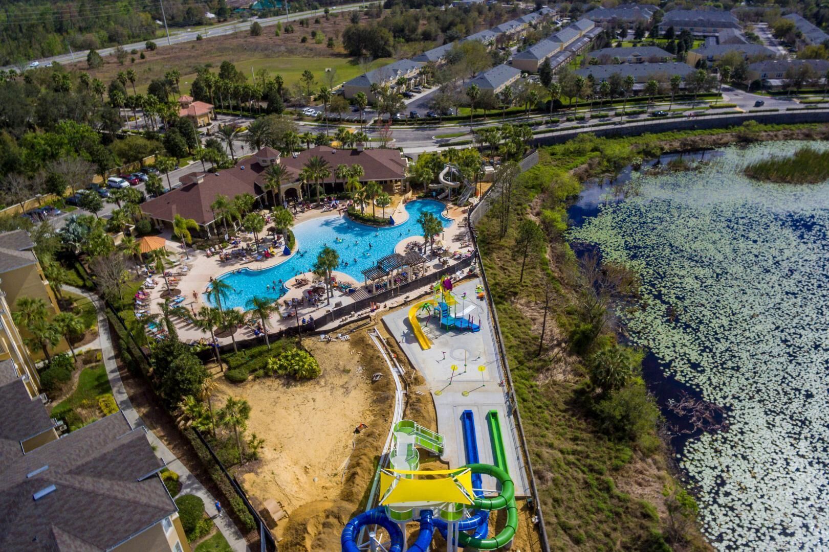 An aerial view of a resort with multiple swimming pools, a water park, and a beach area.